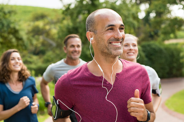 man in a purple shirting with headphones in ears with some friends